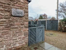An outdoor area with a sign and stone wall at Cobble Cottage Long Marton near Appleby-In-Westmorland
