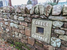 A stone wall with a sign reading Cobble Cottage