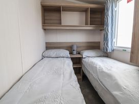 A bedroom with two beds and a nightstand at MC15 in Rhyl
