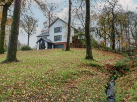 A house on a hillside surrounded by trees and a stream at Chapel Hill in Catlowdy