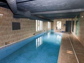 An indoor swimming pool with tiled walls and windows at Chapel Hill in Catlowdy