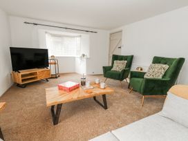 A living room with green armchairs and a coffee table at Long Barn in Burton Bradstock