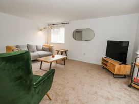 A living room with a sofa, armchair, coffee table, and television at Long Barn in Burton Bradstock