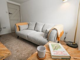 A living room with a sofa and a book on a table at Long Barn in Burton Bradstock