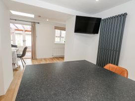 A dining room with a table and television at Long Barn in Burton Bradstock