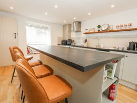 A kitchen with a bar island and appliances at Long Barn in Burton Bradstock