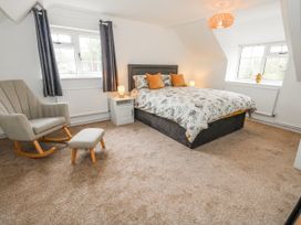 A bedroom with a bed and rocking chair at Long Barn in Burton Bradstock