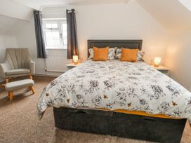 A bedroom with a double bed and armchair at Long Barn in Burton Bradstock
