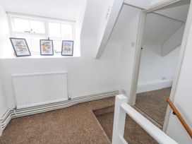 A hallway with framed photographs and a radiator at Long Barn in Burton Bradstock