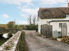 An outdoor view of a bungalow and stone bridge at Long Barn in Burton Bradstock