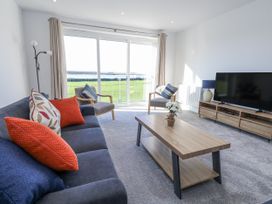 A living room with a sofa, armchair, coffee table and television at Seafern House 36B Poole