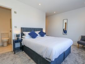 A bedroom with a bed, bedside table, and a bathroom doorway at Seafern House 36B, Poole
