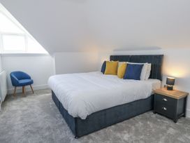 A bedroom with a bed, pillows, nightstand, and an armchair at Seafern House 36B in Poole