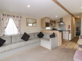 A living room with a sofa and kitchen area at Peaceful in Stranraer