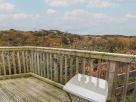 A wooden outdoor patio with a table and chair overlooking a natural landscape at Peaceful in Stranraer