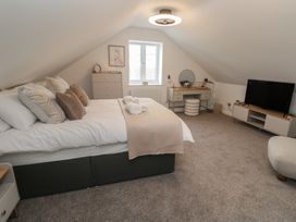 A bedroom with a bed, nightstand, dresser and television at Cosy Retreat