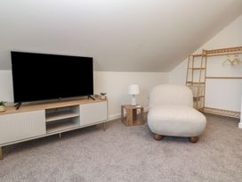 An attic room with a television and an armchair at Cosy Retreat