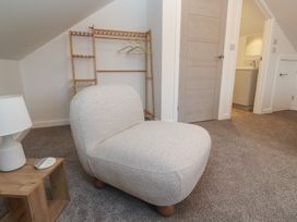 A chair and side table with a lamp in a bedroom at Cosy Retreat