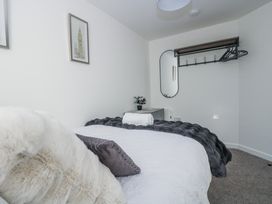 A bedroom with a bed, mirror, and coat rack at Cosy Retreat in Pool