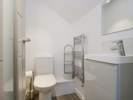 A bathroom with a toilet, sink, towel rail, and mirror at Cosy Retreat in Pool