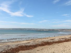 A beach with people walking along the shore at Sea Whispers in Marazion