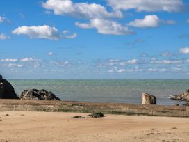 A beach with sand and rocks under a blue sky at 3 Brooks Cottages in Hope Cove