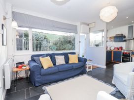 A living room with a blue sofa and kitchen visible at 3 Brook Cottages Hope Cove