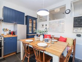 A kitchen with a dining table set and modern appliances at 3 Brook Cottages Hope Cove