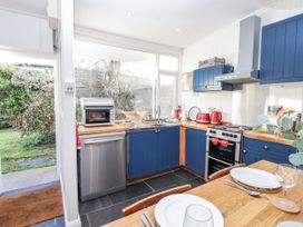 A kitchen with appliances and table at 3 Brook Cottages in Hope Cove