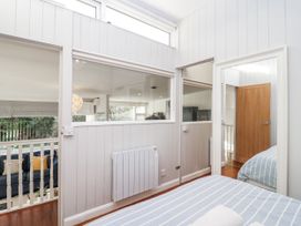 A bedroom featuring a bed, window, and door at 3 Brook Cottages in Hope Cove