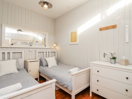A bedroom with two beds and a mirror at 3 Brook Cottages in Hope Cove