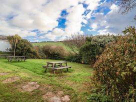 A garden with picnic tables and greenery at 3 Brook Cottages in Hope Cove