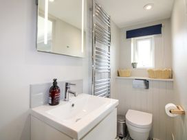 A bathroom with a sink, mirror, toilet, and towel radiator at 3 Brook Cottages in Hope Cove