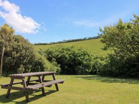 A picnic table with grass and bushes at 3 Brook Cottages in Hope Cove