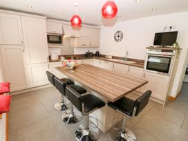 A kitchen with a table and stools at The Old Barn in Pwllheli
