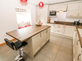 A kitchen with a worktop and bar stool at The Old Barn in Pwllheli