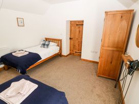 A bedroom with two beds and a wardrobe at The Old Barn in Pwllheli