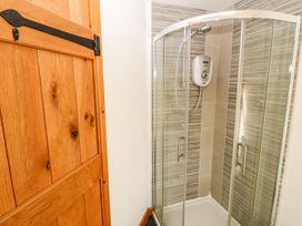 A shower unit with glass doors and wooden door at  in Pwllheli