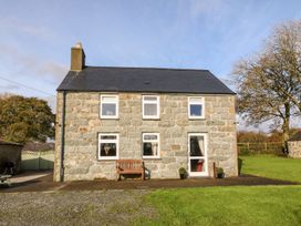 A house with a bench in front and trees at the side in Pwllheli