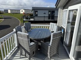 A deck with a round table and six chairs at 30 Wells Close in Berwick-upon-Tweed