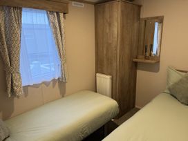 A bedroom with two beds and a cupboard at 30 Wells Close in Haggerston