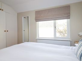 A bedroom with a wardrobe and a window at The Mizzen in St Endellion near Port Isaac