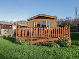 A cabin with a deck and grass area at Bluebell Lodge in Warton