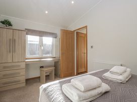 A bedroom with towels on the bed at Bluebell Lodge in Warton