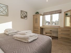 A bedroom with a bed and mirrors at Bluebell Lodge in Warton