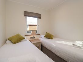 A bedroom with twin beds and a bedside table at Bluebell Lodge in Warton