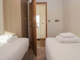 A bedroom with twin beds and a wardrobe at Bluebell Lodge in Warton