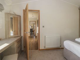 A bedroom with a dresser and an open door at Bluebell Lodge in Warton