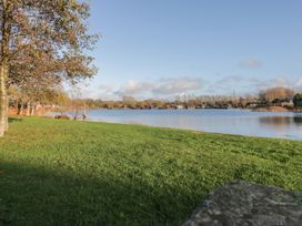 A view of a lake with grassy areas and trees at Bluebell Lodge in Warton
