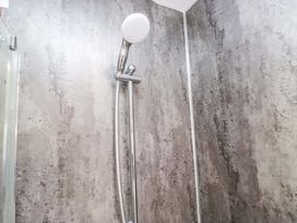 A shower with a showerhead and wall at Bluebell Lodge in Warton